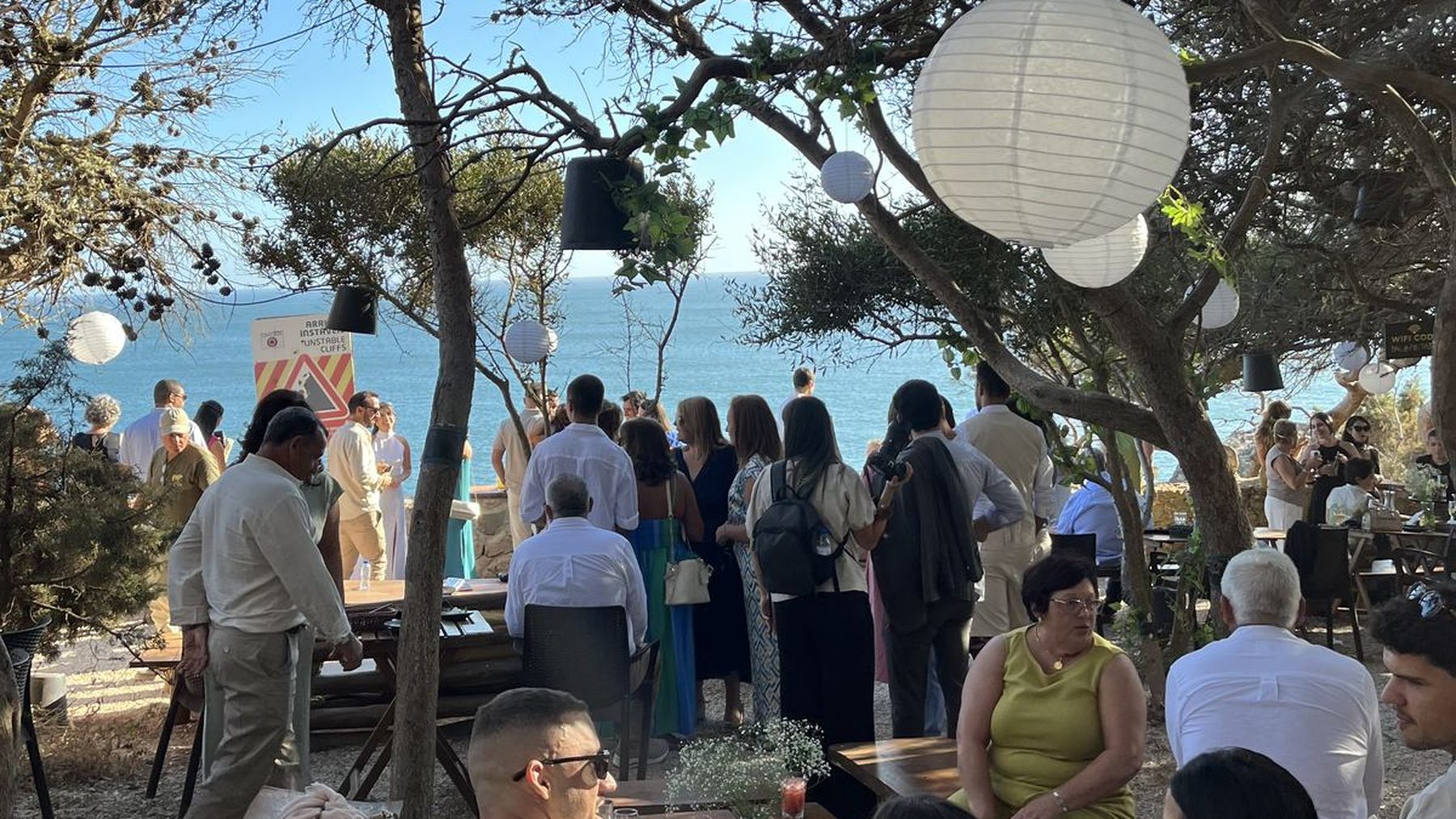Convidados de um casamento diante do mar, sob lanternas brancas, na Palaphita Cascais